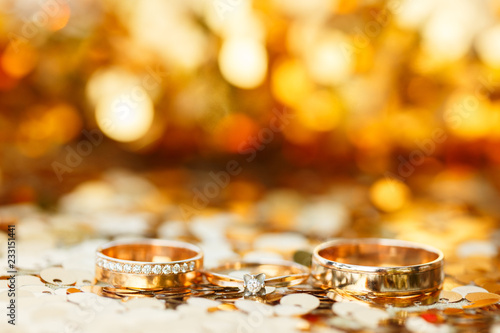 three golden wedding rings with golden bokeh background
