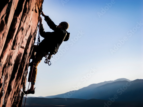 man climbing red rocks