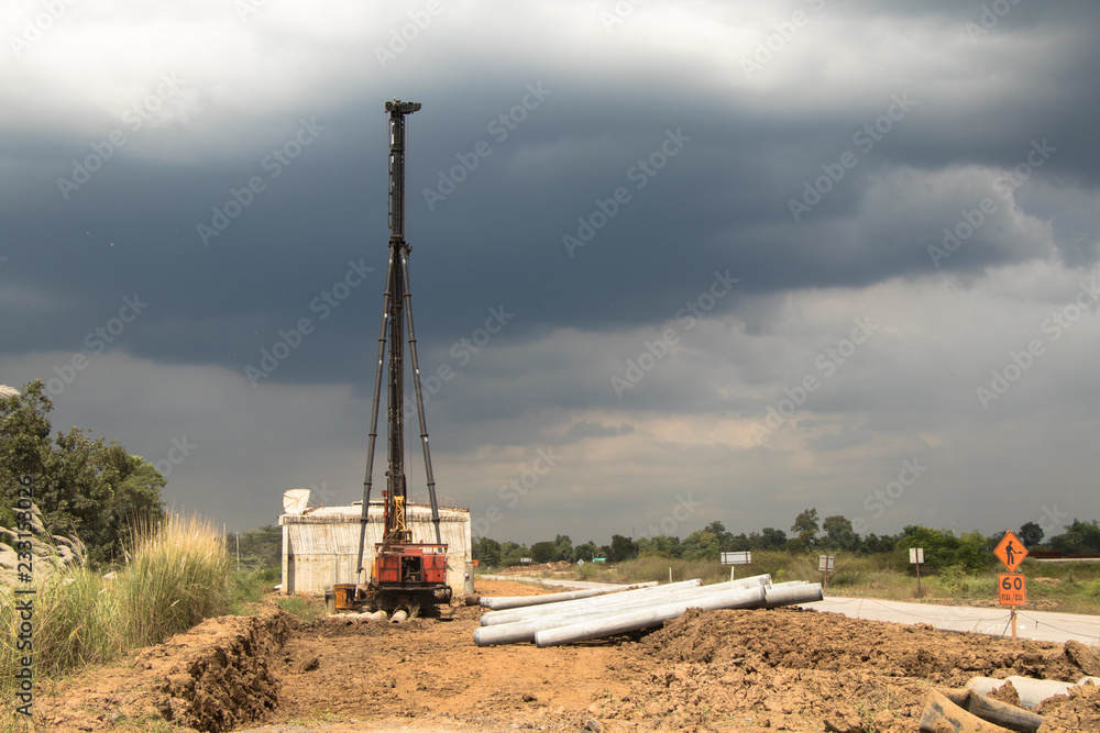 Construction of the bridge and road, crane and tubes  on a ground and dark sky with cloud.