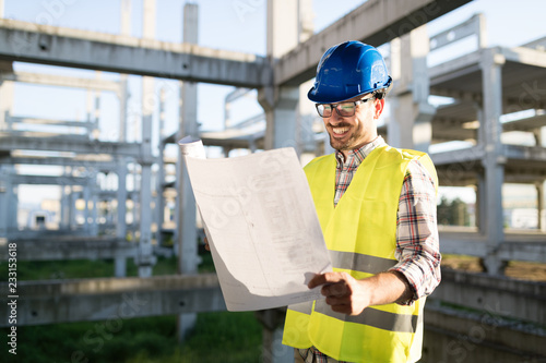 Engineers working on a building site with blue prints © NDABCREATIVITY