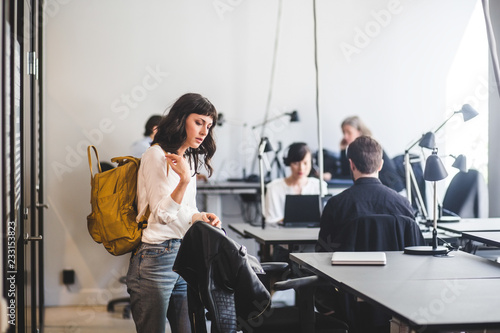 Businesswoman with backpack standing in office photo