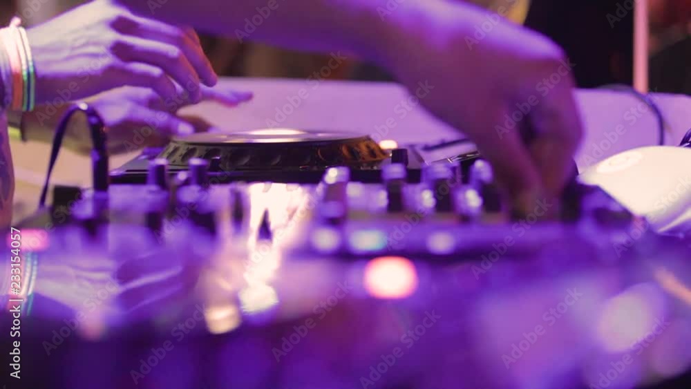 Deejay sta lavorando alla sua consolle mettendo musica per la folla che balla in un locale notturno Deejay sta lavorando alla sua consolle mettendo musica per la folla che balla in un locale notturno