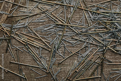 Top view of cooper and silver-colored nails on dark wooden table