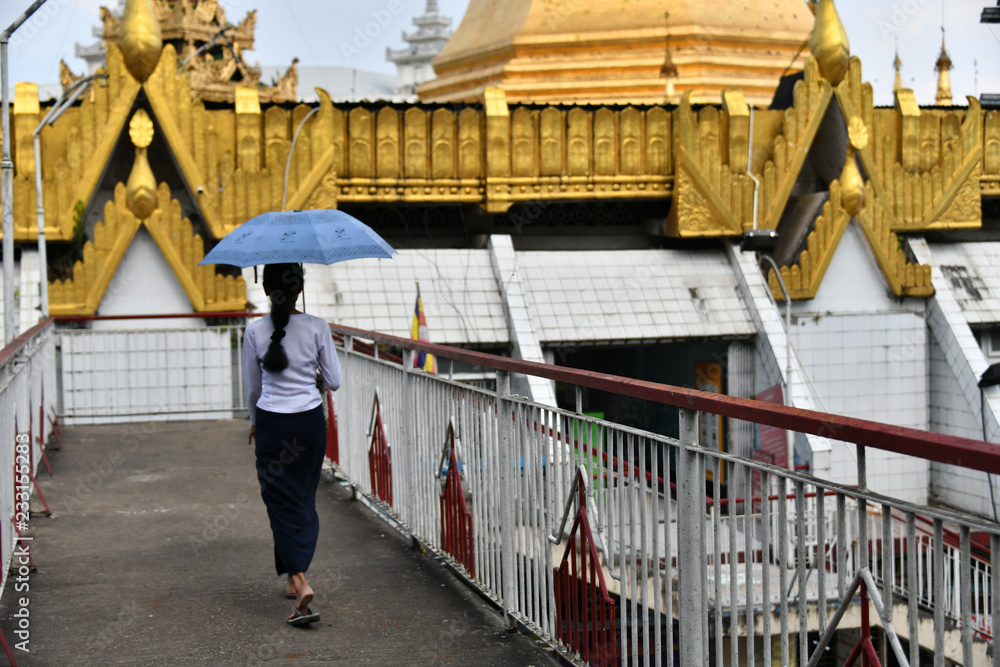 A woman wearing traditional dress (longyi) goind to Sule Pagoda in the center of Yangon