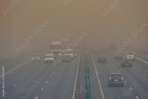 Dense fog and poor visibility on the road. Dangerous driving situations. View on highway traffic in misty morning. Low visibility. Smoke on the road. Semi-trailer truck and cars driving trough haze.