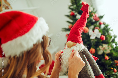 Portrait of beautiful woman with Santa Claus sitting near Christmas tree.