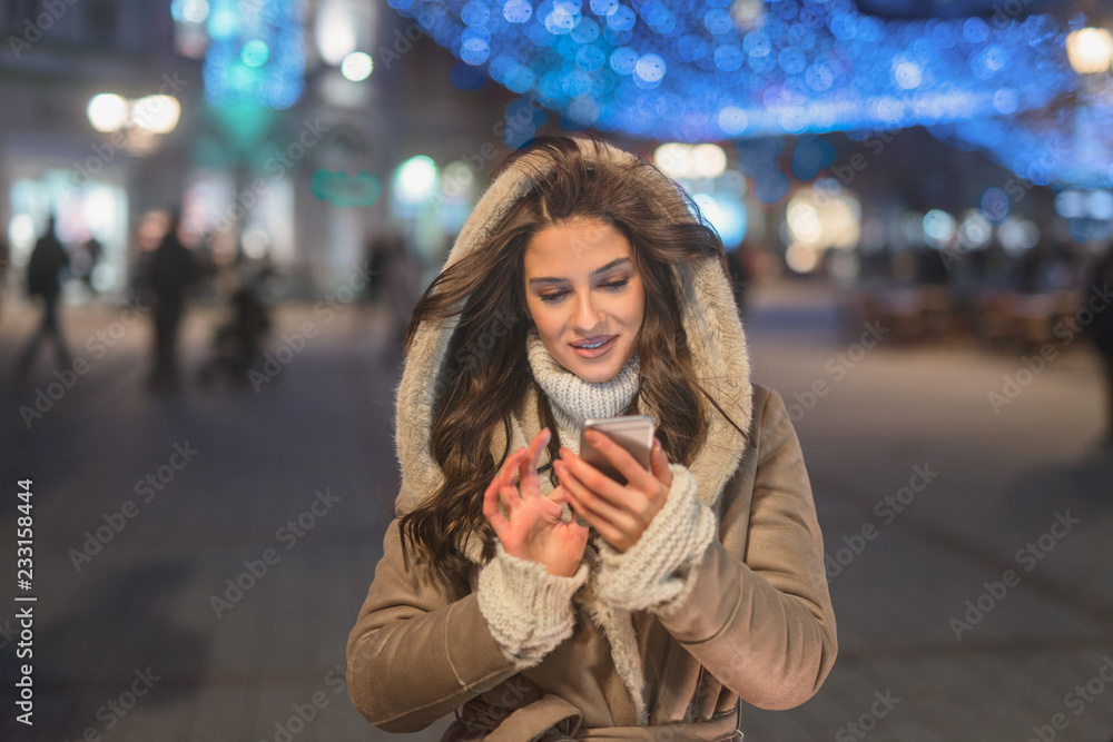 Fototapeta premium Woman using smart phone for texting while standing in the street.