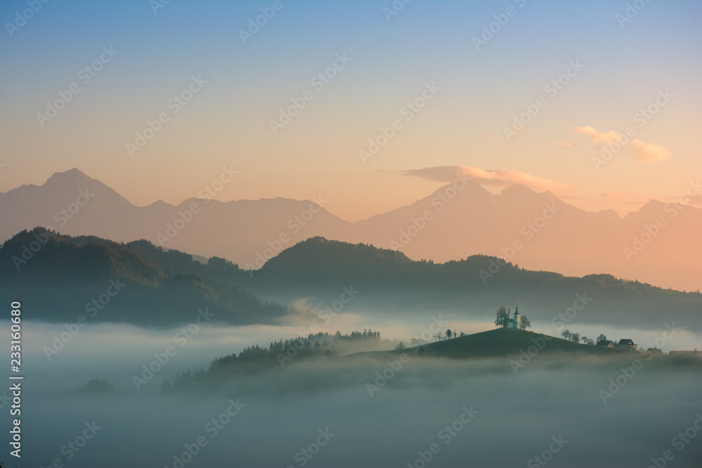 Beautiful sunrise landscape of Saint Thomas Church in Slovenia on hilltop in the morning fog
