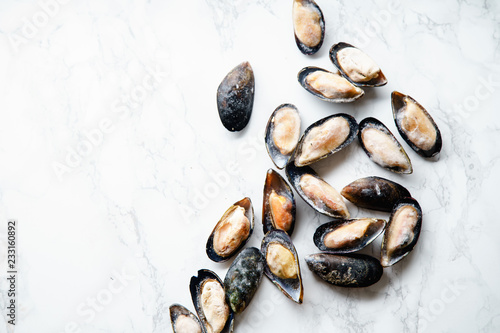 Top view with frozen mussels on white marble background with copy space