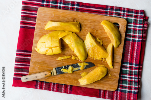 Fototapeta Naklejka Na Ścianę i Meble -  Mango Fruit with Slices Cut with Knife on Wooden Surface Board.