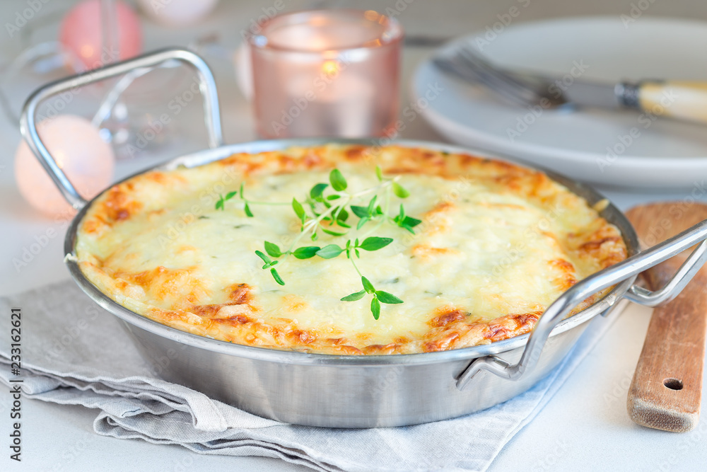 Cheesy scalloped potatoes or potato gratin in baking dish, holiday theme, horizontal Cheesy scalloped potatoes or potato gratin in baking dish, holiday theme, horizontal