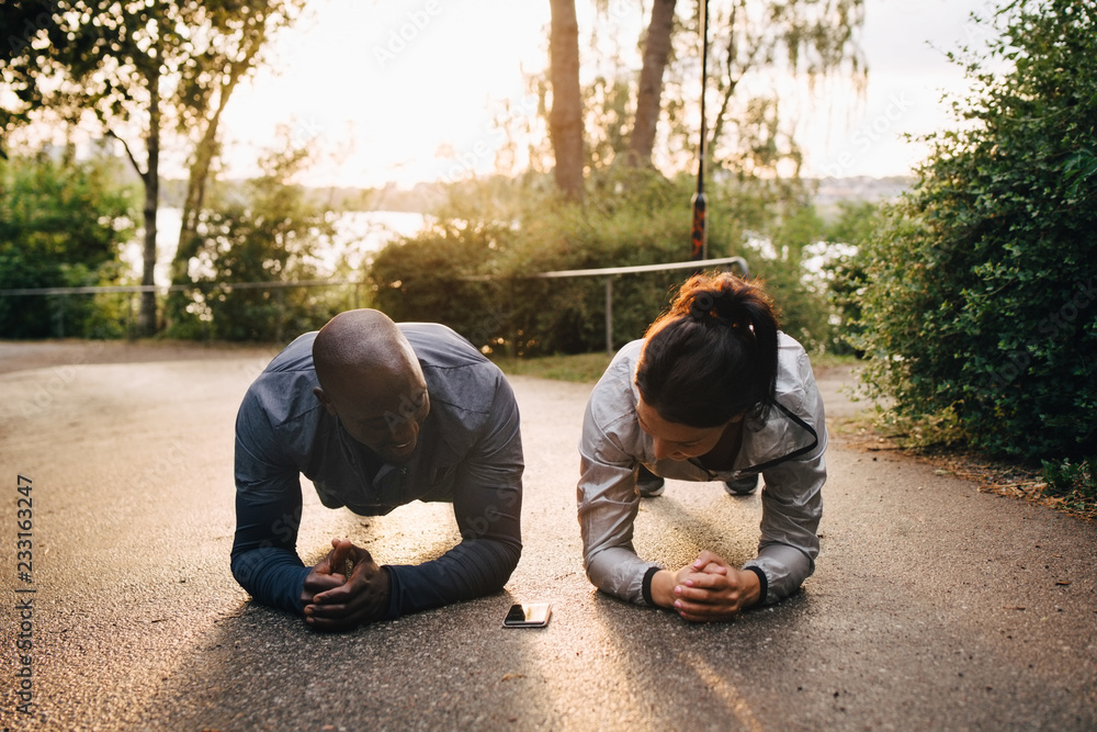 © Maskot - Athletes doing plank exercise on road in park during sunset © Maskot - Athletes doing plank exercise on road in park during sunset