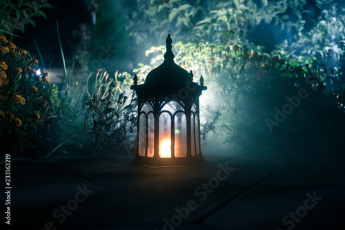 Retro style lantern at night. Beautiful colorful illuminated lamp at the balcony in the garden. Selective focus