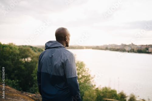 Male athlete looking at sea while standing on hill