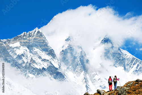 Hiker with backpacks reaches the summit of mountain peak. Success freedom and happiness achievement in mountains. Active sport concept.