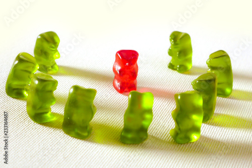 sweet candy gummy teddy bears representing group of students or work colleagues bullying and mobbing helpless victim in harassment and abuse social problem concept