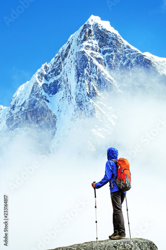 Hiker with backpacks reaches the summit of mountain peak. Success, freedom and happiness, achievement in mountains. Active sport concept.