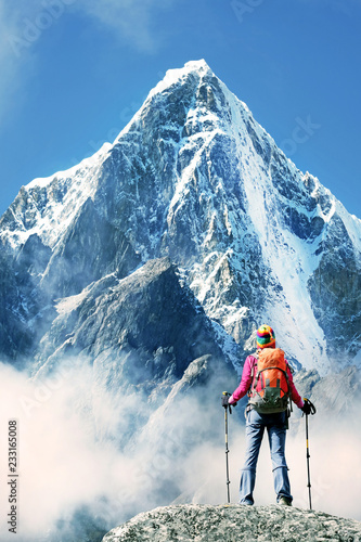 Hiker with backpacks reaches the summit of mountain peak. Success, freedom and happiness, achievement in mountains. Active sport concept.