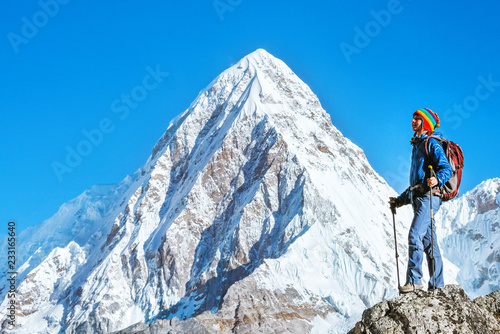 Hiker with backpacks reaches the summit of mountain peak. Success, freedom and happiness, achievement in mountains. Active sport concept.