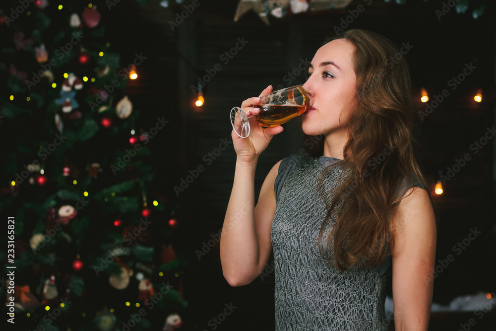 Beautiful girl drinking champagne during chrismas celebration.