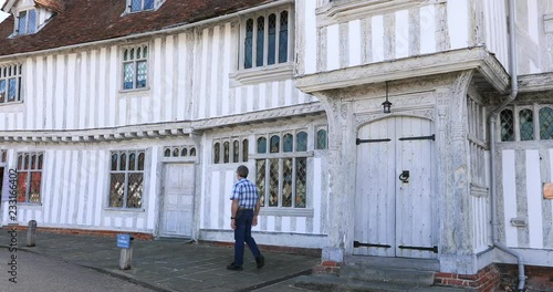 Lavenham England man at Guild House historic village. Lavenham village, civil parish in Suffolk, England. 15th century church, half timbered crooked unlevel medieval cottages and business. photo