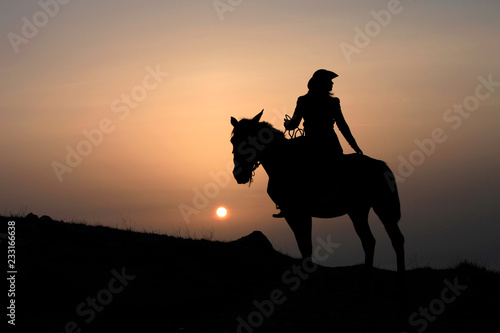 Silhouette of a horsewoman on a horse at sunset © yanakoroleva27
