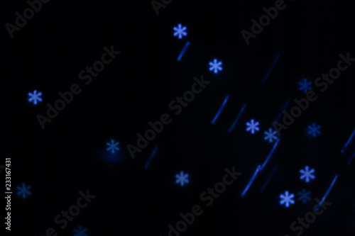 Beautiful figured boke from a garland of cold light in the form of a snowflake on a dark background. Conceptual New Year's photo.