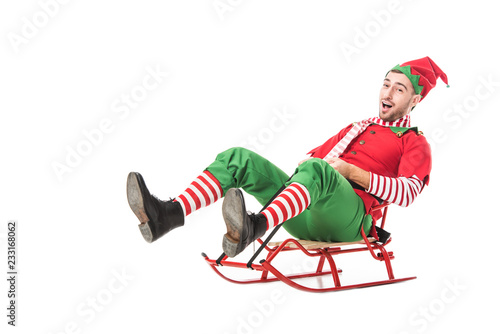 Cuadro en lienzo cheerful excited man in christmas elf costume riding sleigh isolated on white ba
