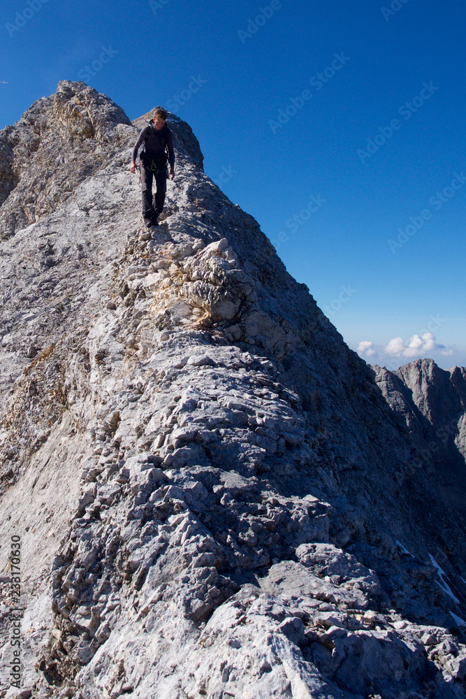 Mann läuft auf Bergrücken, Bergwanderung in den Alpen