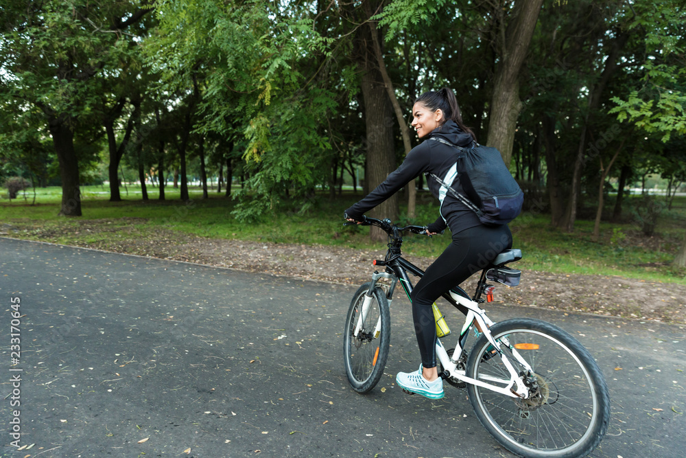 Beautiful woman walking on bicycle in the park outdoors. Beautiful woman walking on bicycle in the park outdoors.