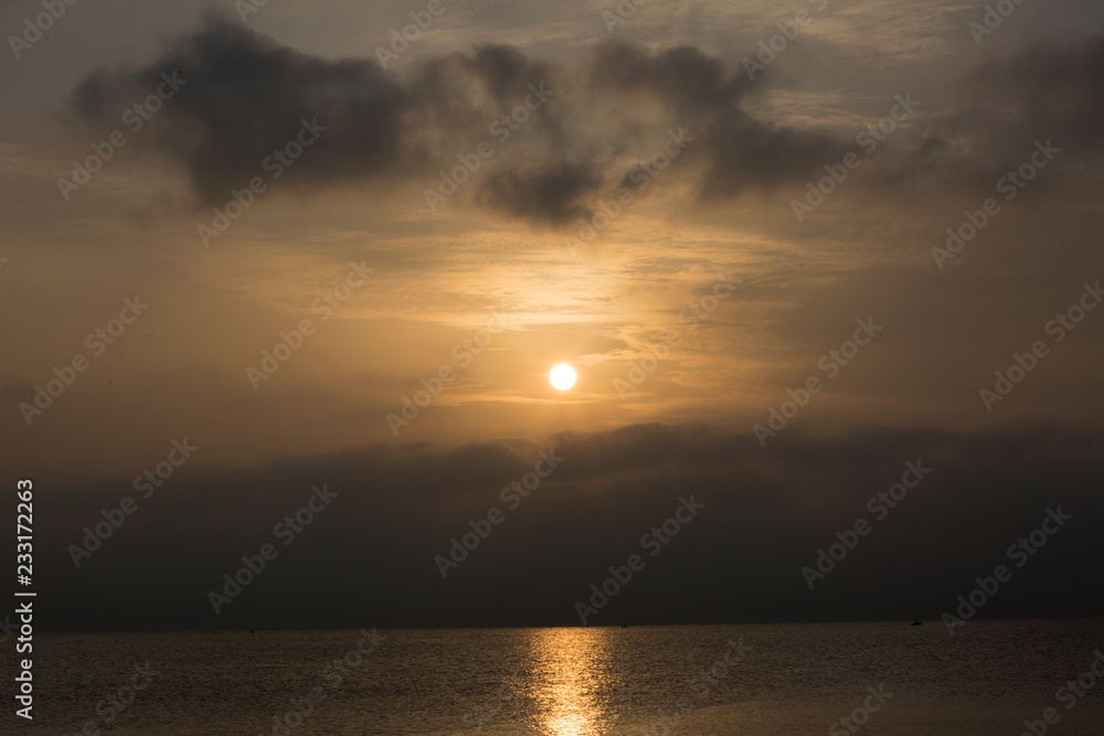 Sunrise among gray clouds in the sky above the sea