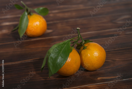 tangerines with green leaves on a wooden background, still life