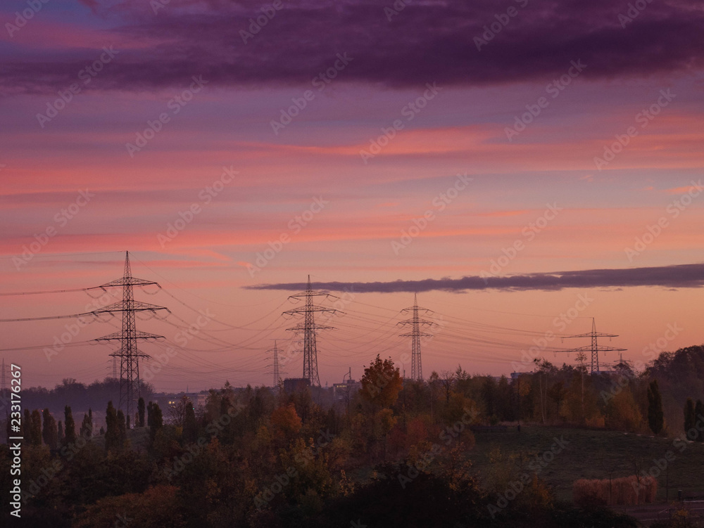 Stromtrasse im Ruhrgebiet bei rötlich violettem Morgenlicht