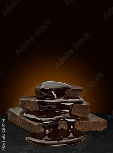 Chocolate sauce flow over cracked chocolate blocks on brown background