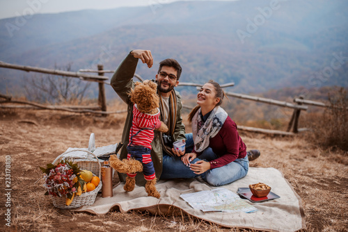 Couple sitting at picnic and playing with dog. photo