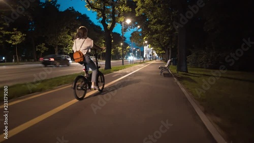 Wallpaper Mural Tracking shot young woman biking riding a bike on the street Arch of Triumph Bucharest at dusk sunset Torontodigital.ca