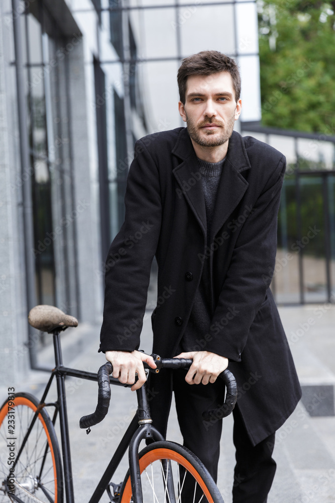 Handsome young business man walking outdoors with bicycle. Handsome young business man walking outdoors with bicycle.