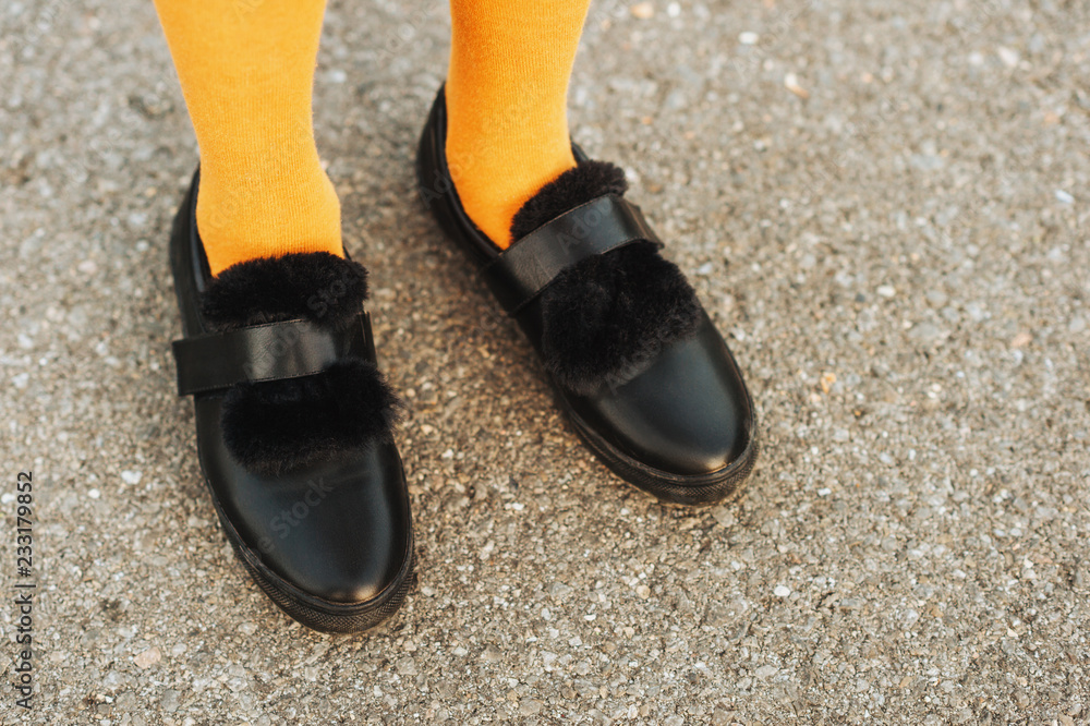 Black strap leather shoes with faux fur and yellow tights on girl's feet