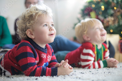 Lovely twins sitting on the carpet, wearing christmas clothes