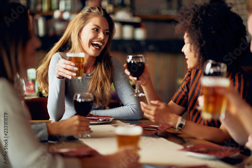Canvas Print Multicultural friends sitting in restaurant and drinking wine and beer