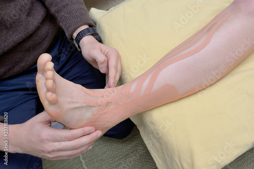 Physiotherapist applying kinesiology tapes photo