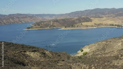 A blue lake in between hills with power boats and kayaks