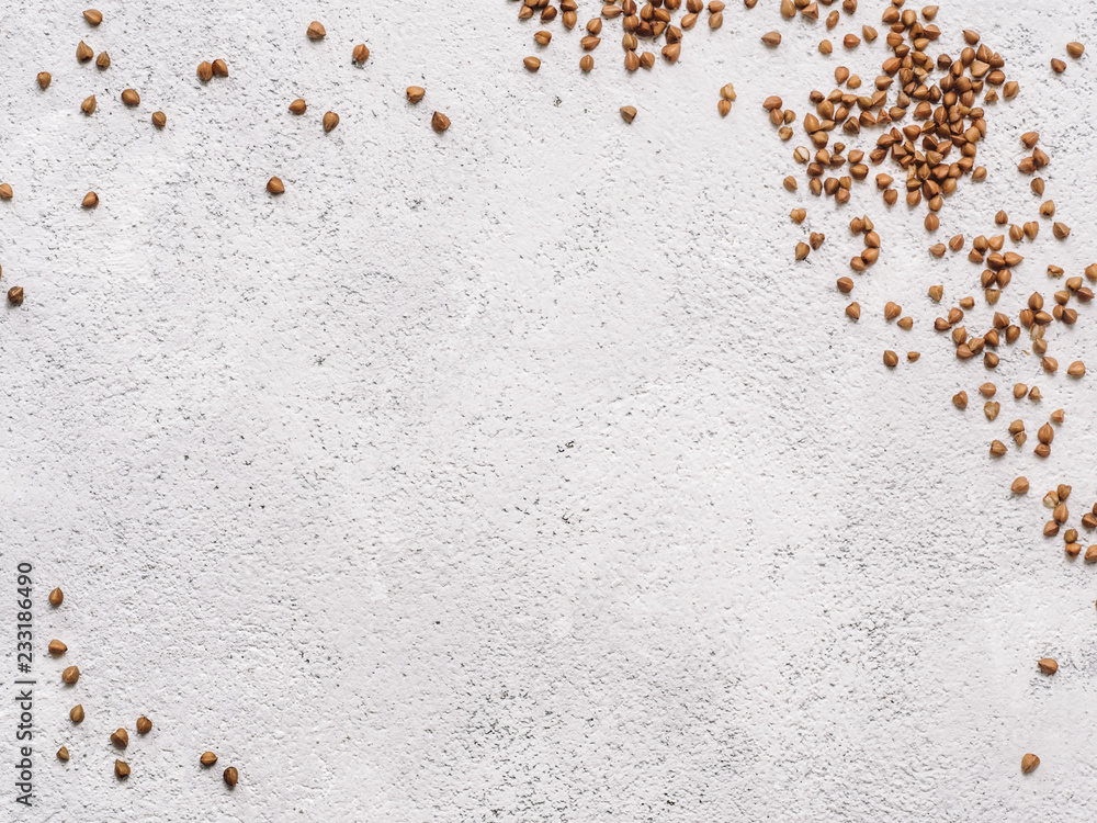 Buckwheat with copy space. Brown raw buckwheat grain on gray concrete textured background. Top view or flat lay. Copy space. Healthy food and diet concept. Buckwheat background.