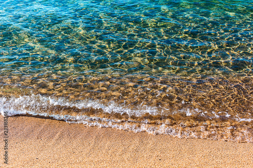 Sandy beach of warm sea. Transparent turquoise water, soft wave, sunlight reflecting on sea bottom