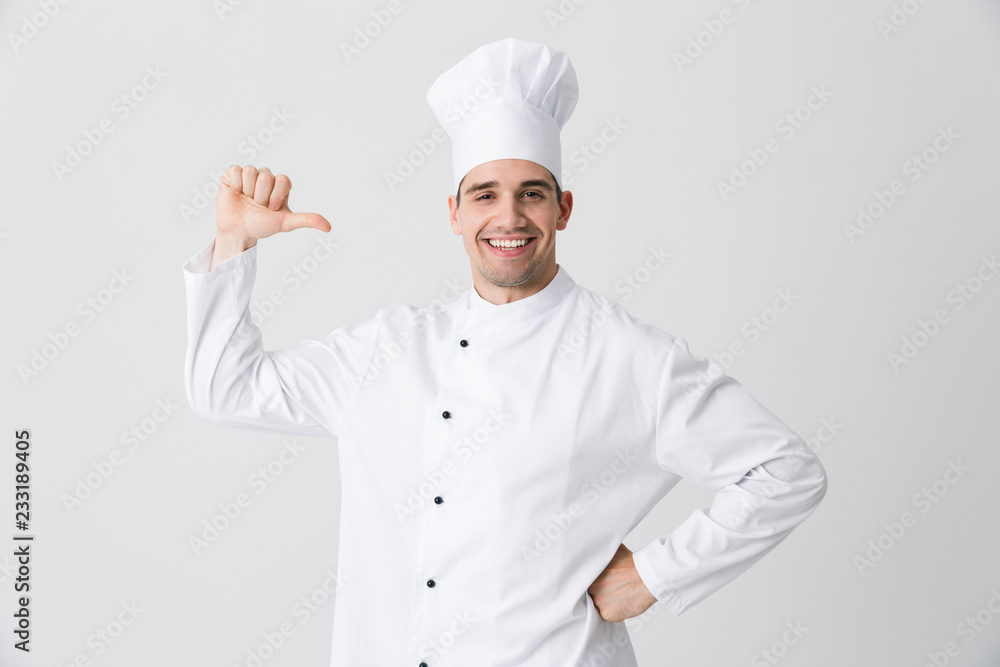 Excited young man chef indoors isolated over white wall background pointing. Excited young man chef indoors isolated over white wall background pointing.