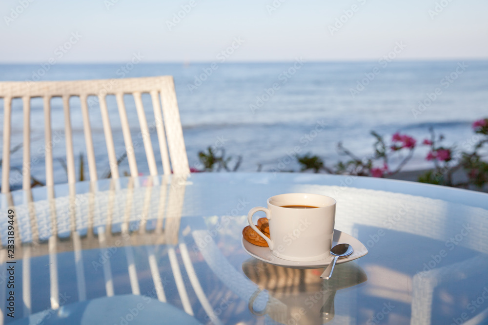 A Cup of coffee on the glass table. Cafe by the sea.