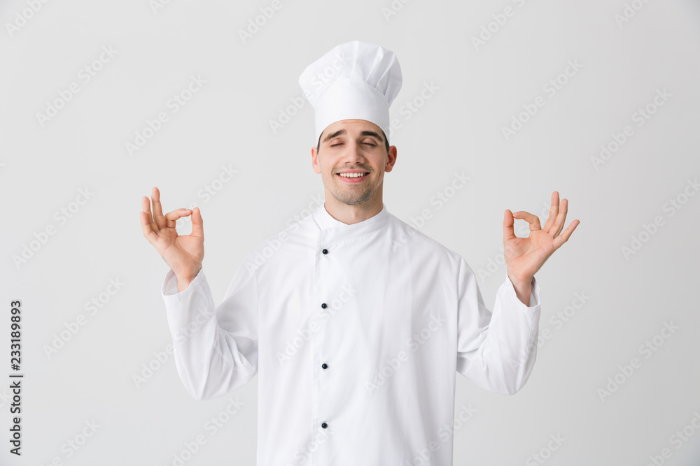Handsome young man chef indoors isolated over white wall background. Handsome young man chef indoors isolated over white wall background.
