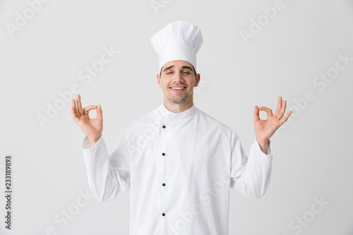 Handsome young man chef indoors isolated over white wall background.