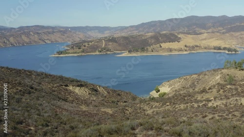 A blue lake in between hills with power boats and kayaks
