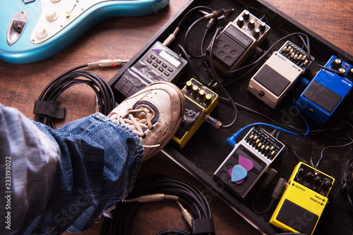 Stepping on a electric guitar audio processing effects on a studio or stage floor. Electric guitar and stomp box type effectors and cables on studio floor. Intentionally shot with low key tone. photo